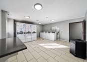 Thumbnail 50 of 75 - A clean, modern laundry room with a washer and dryer on the wall and a flat screen TV on the counter.