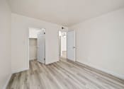 Thumbnail 18 of 18 - A room with white walls and wood flooring with two doors open.