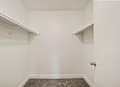 Thumbnail 16 of 18 - A small, empty room with a carpeted floor and a door.