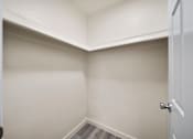 Thumbnail 7 of 18 - A white door is open to a small, empty room with white walls.