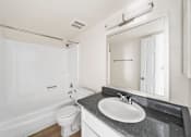 Thumbnail 16 of 18 - A white bathroom with a black countertop and a white toilet.