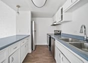 Thumbnail 10 of 18 - A kitchen with white cabinets and a wooden floor.