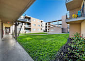 Thumbnail 1 of 5 - A view of a balcony with a yellow chair and a building in the background.