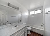 Thumbnail 8 of 12 - A white bathroom with a sink, toilet, and bathtub.