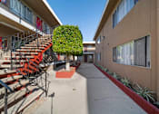Thumbnail 7 of 12 - A red staircase with a metal railing is on the left side of a concrete walkway.