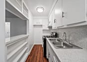 Thumbnail 11 of 12 - A kitchen with white cabinets and a wooden floor.