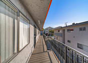 Thumbnail 3 of 4 - A long balcony with a black railing and a white wall.