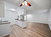 Thumbnail 9 of 10 - A kitchen with white cabinets and a wooden floor.