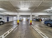 Thumbnail 1 of 10 - A parking garage with cars parked on both sides of the aisle.
