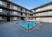 Thumbnail 5 of 10 - A swimming pool in the middle of a courtyard surrounded by apartment buildings.