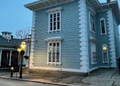 Thumbnail 3 of 7 - A blue house with white trim and a black iron railing on the porch.