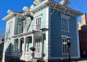 Thumbnail 1 of 7 - A blue house with a white porch and a sign that says "FRANK".