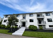 Thumbnail 1 of 10 - A white two-story building with black railings and windows.