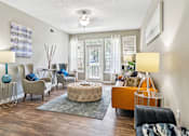 Thumbnail 4 of 24 - A living room with a grey rug and a brown ottoman.