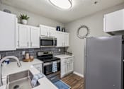 Thumbnail 3 of 27 - A kitchen with white cabinets and a grey refrigerator at The Atlantic Canton Ridge, Georgia