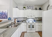 Thumbnail 2 of 24 - A white kitchen with a sink and a refrigerator.