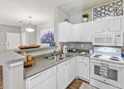 Thumbnail 1 of 24 - A kitchen with white cabinets and appliances.