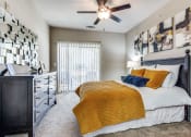 Thumbnail 10 of 25 - a bedroom with a bed and a ceiling fan at Village of Hawks Creek Apartments, Westworth Village Texas