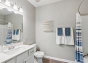 Thumbnail 7 of 27 - A white bathroom with a white toilet, sink, and a blue and white towel hanging on the wall at The Atlantic Canton Ridge, Georgia