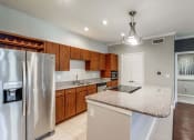 Thumbnail 8 of 17 - Kitchen with granite countertops and wooden cabinets at Vintage Park Apartments, Houston