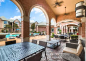 Thumbnail 5 of 17 - Patio with tables and chairs and a pool in the background at Vintage Park Apartments, Texas 77070