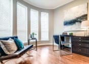 Thumbnail 9 of 17 - Living room with a leather couch and a desk and three windows at Vintage Park Apartments, Houston, TX