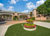 Thumbnail 1 of 17 - Courtyard with a large flower bed and a building in the background at Vintage Park Apartments, Houston