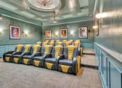 Thumbnail 11 of 17 - Theater room with blue and yellow chairs and a chandelier at Vintage Park Apartments, Texas