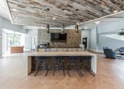 Thumbnail 5 of 14 - Kitchen with bar stools and a tv in a room with a living room  at Harrison Grande, Cary, North Carolina