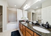 Thumbnail 20 of 23 - A bathroom with a white tub and sink at The Atlantic Stone Oak Apartments, San Antonio
