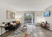 Thumbnail 5 of 19 - A living room with a black couch, a rug, and a TV mounted on the wall at The Atlantic Loring Heights, Atlanta, Georgia