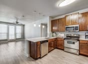Thumbnail 9 of 12 - Empty kitchen with wooden cabinets and stainless steel appliances at The Atlantic Highland Park, Dallas, 75209