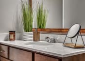 Thumbnail 11 of 12 - Bathroom sink with a mirror and plants on it at The Atlantic Highland Park, Dallas, TX