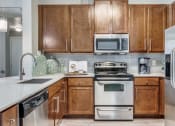 Thumbnail 8 of 12 - Kitchen with stainless steel appliances and wooden cabinets at The Atlantic Highland Park, Dallas