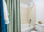 Thumbnail 9 of 23 - A white toilet sits next to a bathtub in a bathroom at Boca Colony Apartments, Florida, 33433