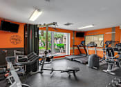 Thumbnail 8 of 23 - A gym with orange walls and a variety of equipment at Boca Colony Apartments, Florida