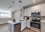 Thumbnail 34 of 34 - A modern kitchen with white cabinets and stainless steel appliances.