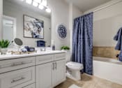 Thumbnail 33 of 34 - A bathroom with a white toilet and a blue shower curtain.