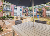 Thumbnail 12 of 34 - A patio with a table and chairs under an umbrella.