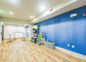 Thumbnail 23 of 34 - A room with a blue wall and wooden flooring, equipped with exercise bikes and other fitness equipment  at The Atlantic Memorial, Houston