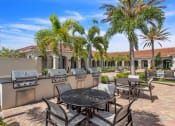 Thumbnail 16 of 29 - a patio with a table and chairs and barbecue grills at The Atlantic Palms at Tradition, Port St Lucie