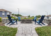 Thumbnail 13 of 15 - Stone patio with blue chairs and a stone fire pit at The Atlantic Mountain Island, Charlotte, North Carolina