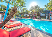Thumbnail 1 of 34 - A pool with red chairs and a palm tree at Reserve at Canyon Creek,San Antonio, Texas