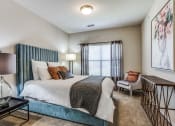 Thumbnail 22 of 25 - a bedroom with a bed and a chair and a window at Village of Hawks Creek Apartments, Westworth Village