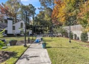 Thumbnail 15 of 16 - Backyard with a sidewalk and a yard with trees and a fence at The Atlantic Briarcliff, Atlanta, Georgia