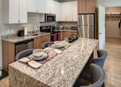 Thumbnail 37 of 43 - Apartments In Downtown Kalamazoo For Rent - 400 Rose - Kitchen With Granite Kitchen Island, Wood-Style Flooring, Sleek White Cabinets, And Stainless-Steel Appliances