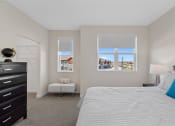 Thumbnail 4 of 30 - a bedroom with a bed and a dresser and two windows at Tivoli Green Apartments & Townhomes, Mount Pleasant, WI