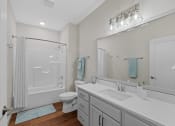 Thumbnail 26 of 30 - a white bathroom with a large mirror and a white toilet and shower at Tivoli Green Apartments & Townhomes, Mount Pleasant, WI