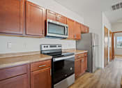 Thumbnail 13 of 30 - A kitchen with wooden cabinets and stainless steel appliances.