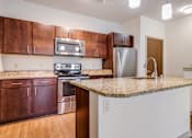 Thumbnail 24 of 30 - A kitchen with brown cabinets and a granite countertop.